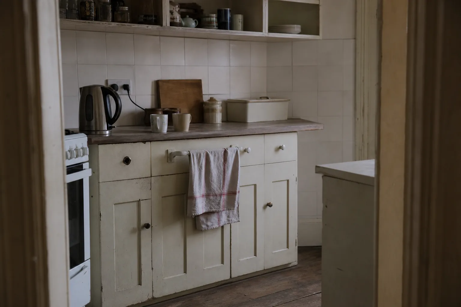 Two mugs beside a kettle on a kitchen counter in early morning light, one of them used