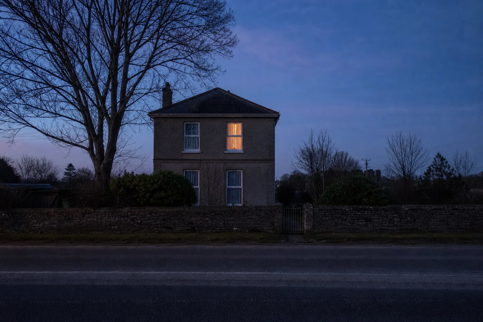 An ordinary house at dusk seen from across the street, one upstairs window lit